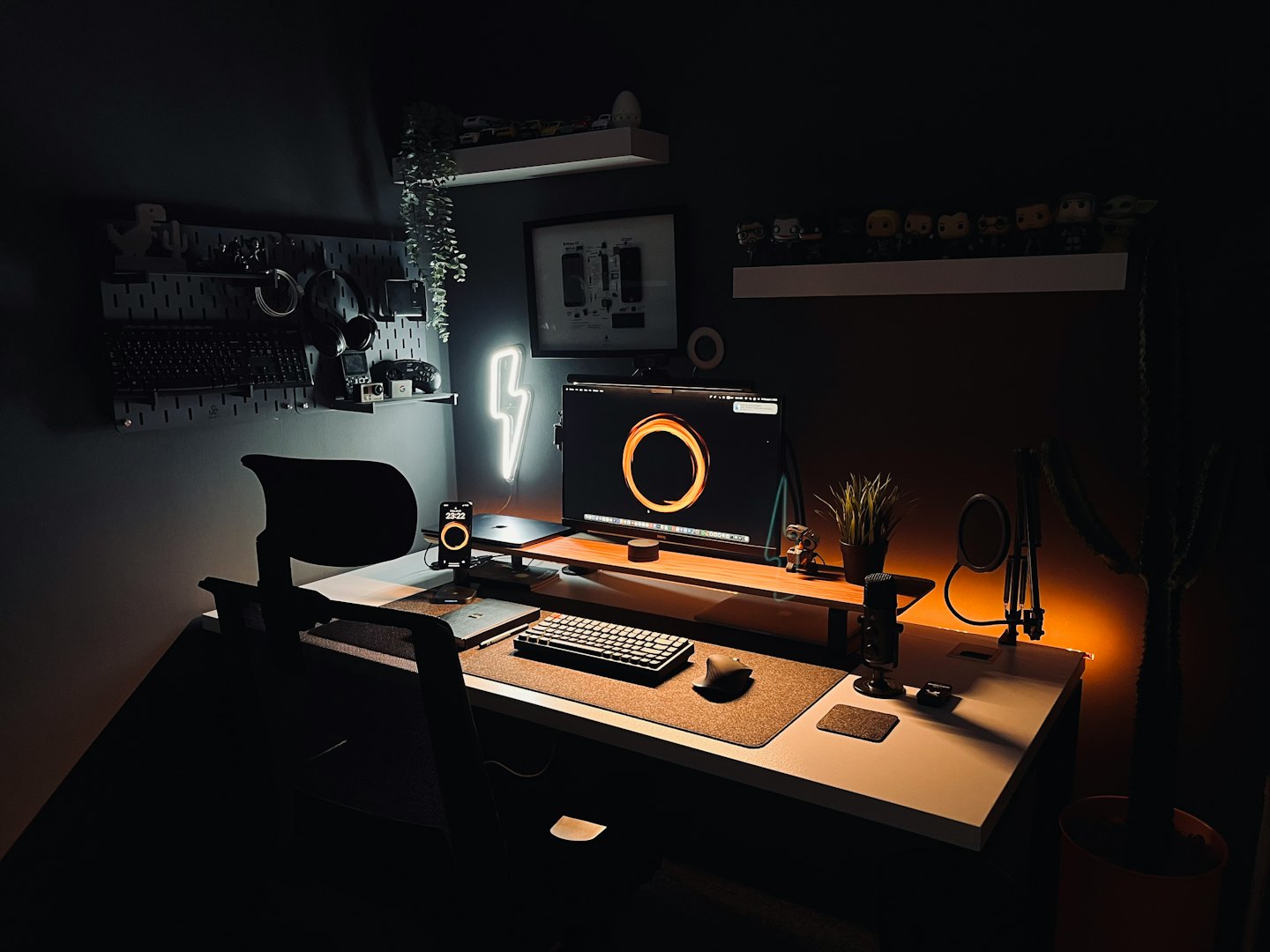 Modern home office desk with computer, microphone, and neon sign.